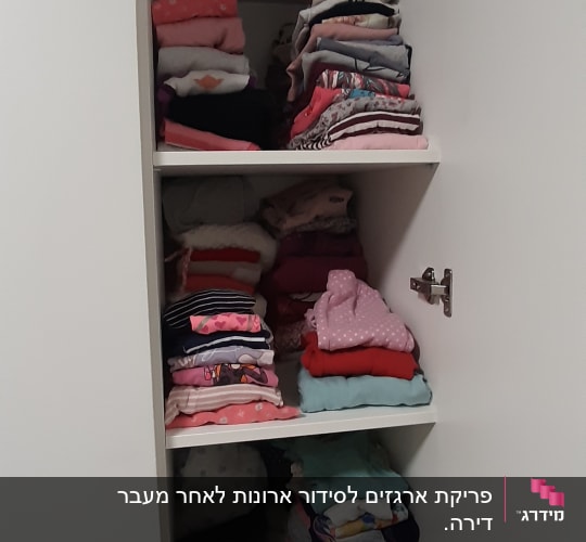 בגדים מקופלים בארון לבן עם מדפים